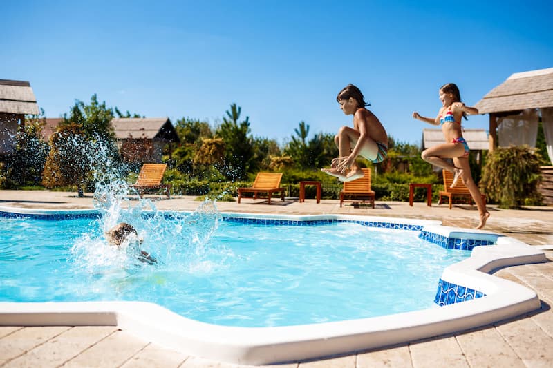 Trois enfants sautent dans une magnifique piscine d'extérieur