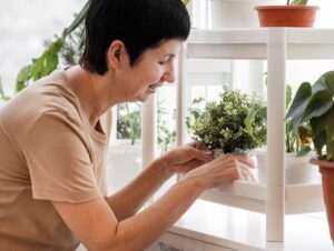 Une femme souri en installant ses plantes d'intérieurs